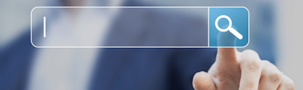 Nahaufnahme einer Person, die auf das Lupensymbol in einer Online-Suchleiste drückt und damit eine Suchaktion anzeigt.