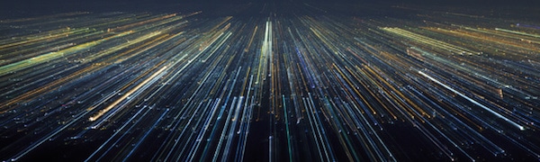 Eine Stadtlandschaft bei Nacht mit horizontal verlaufenden Lichtern, die einen dynamischen, verschwommenen Effekt erzeugen.