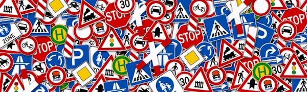 Eine Sammlung verschiedener Verkehrszeichen in unterschiedlichen Formen, Farben und Symbolen, zufällig verstreut.