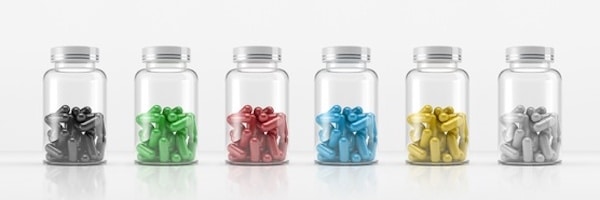 Sechs Glasgefäße enthalten jeweils Wäscheklammern in verschiedenen Farben: Schwarz, Grün, Rot, Blau, Gelb und Weiß, die in einer Reihe auf einer weißen Fläche angeordnet sind.