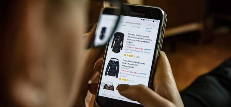 Eine Person durchsucht Amazon auf einem Smartphone und sieht sich Produktlisten und Bewertungen an.