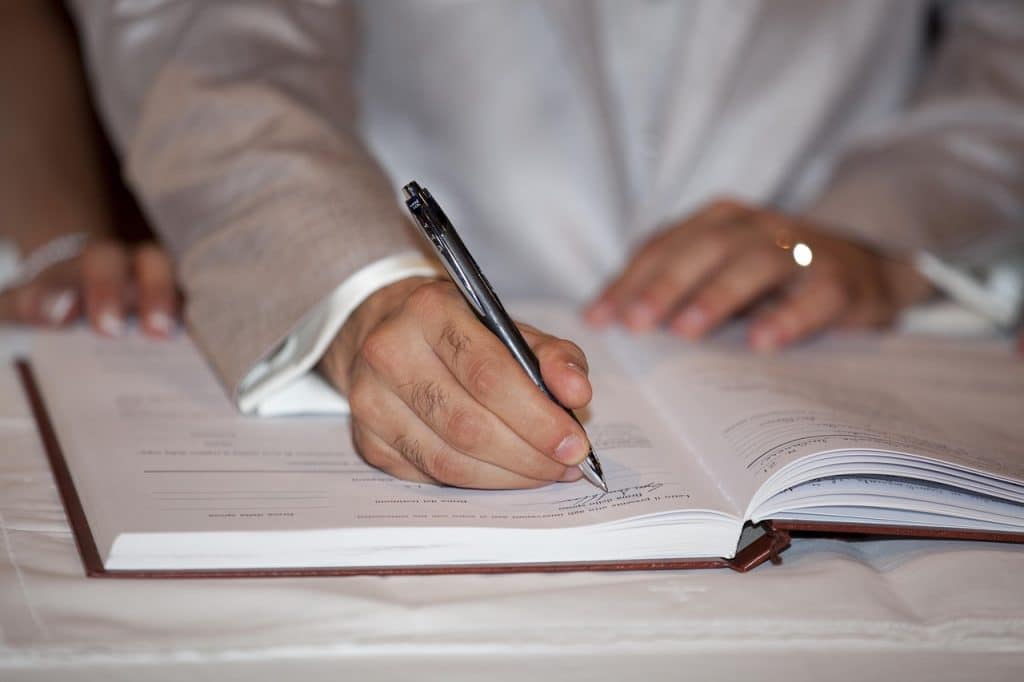 Hand setzt Unterschrift unter einen Vertrag — Symbolbild für die Prüfung des Arbeitsvertrags vor der Unterschrift