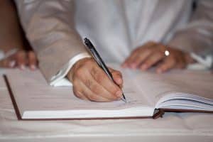 Hand setzt Unterschrift unter einen Vertrag — Symbolbild für die Prüfung des Arbeitsvertrags vor der Unterschrift