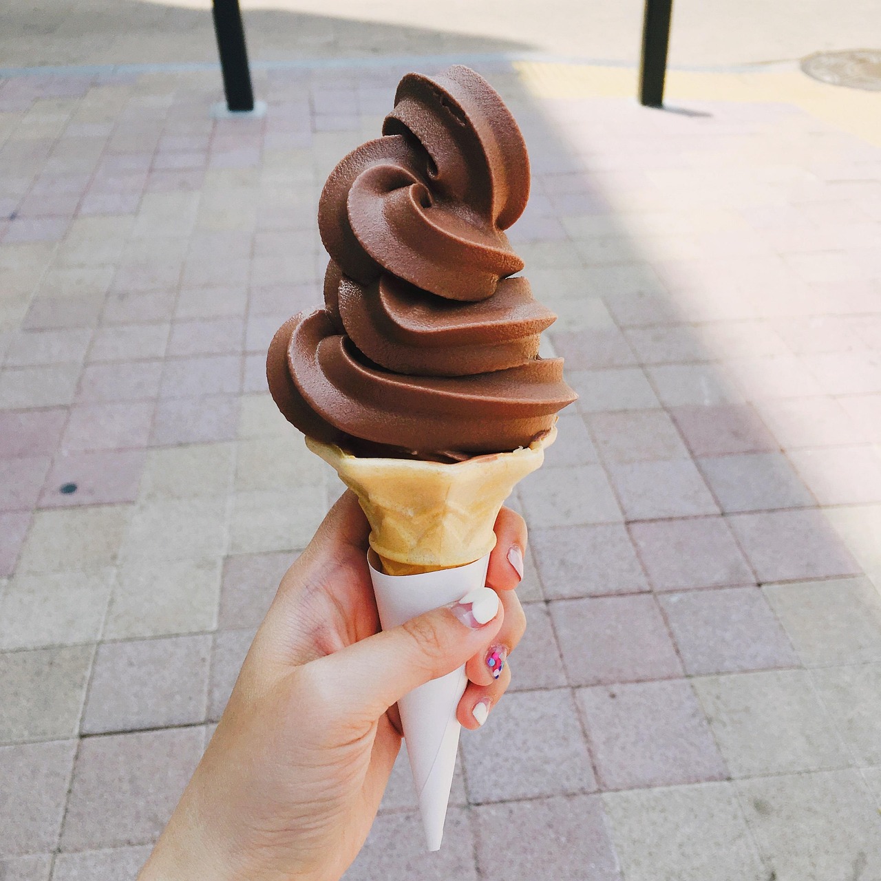 A soft-serve chocolate ice cream in hand on a sunny street—a symbolic image of a summer job