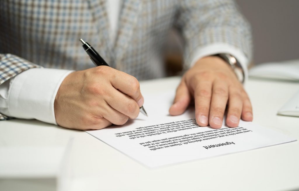 Person unterschreibt einen Vertrag am Schreibtisch