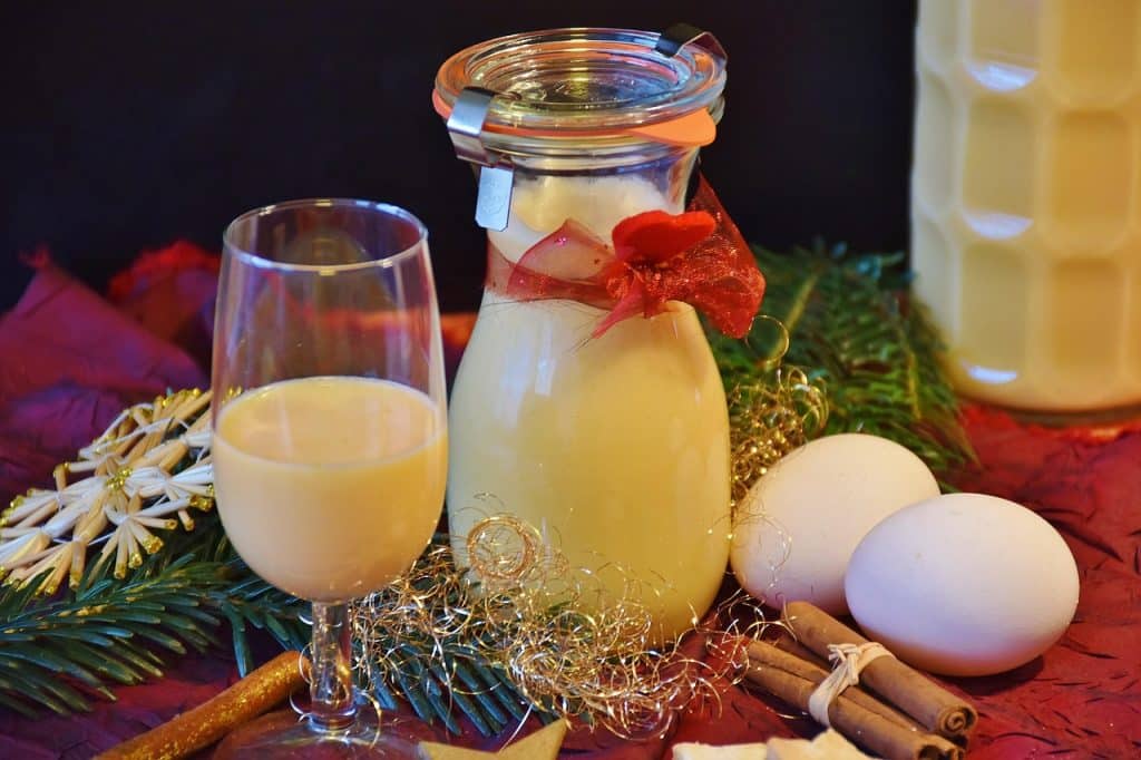 Glas und Flasche mit cremigem gelbem Likör neben Eiern