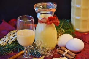 Glas und Flasche mit cremigem gelbem Likör neben Eiern