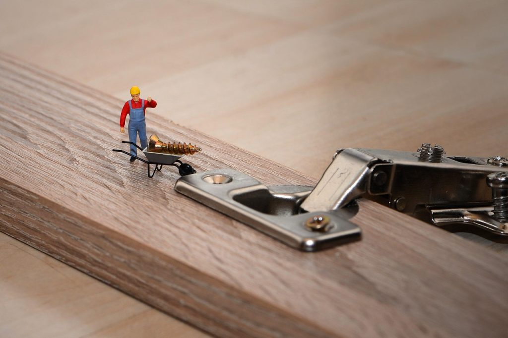 Miniaturfigur schraubt an einem Moebelbeschlag