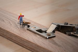 Miniaturfigur schraubt an einem Moebelbeschlag